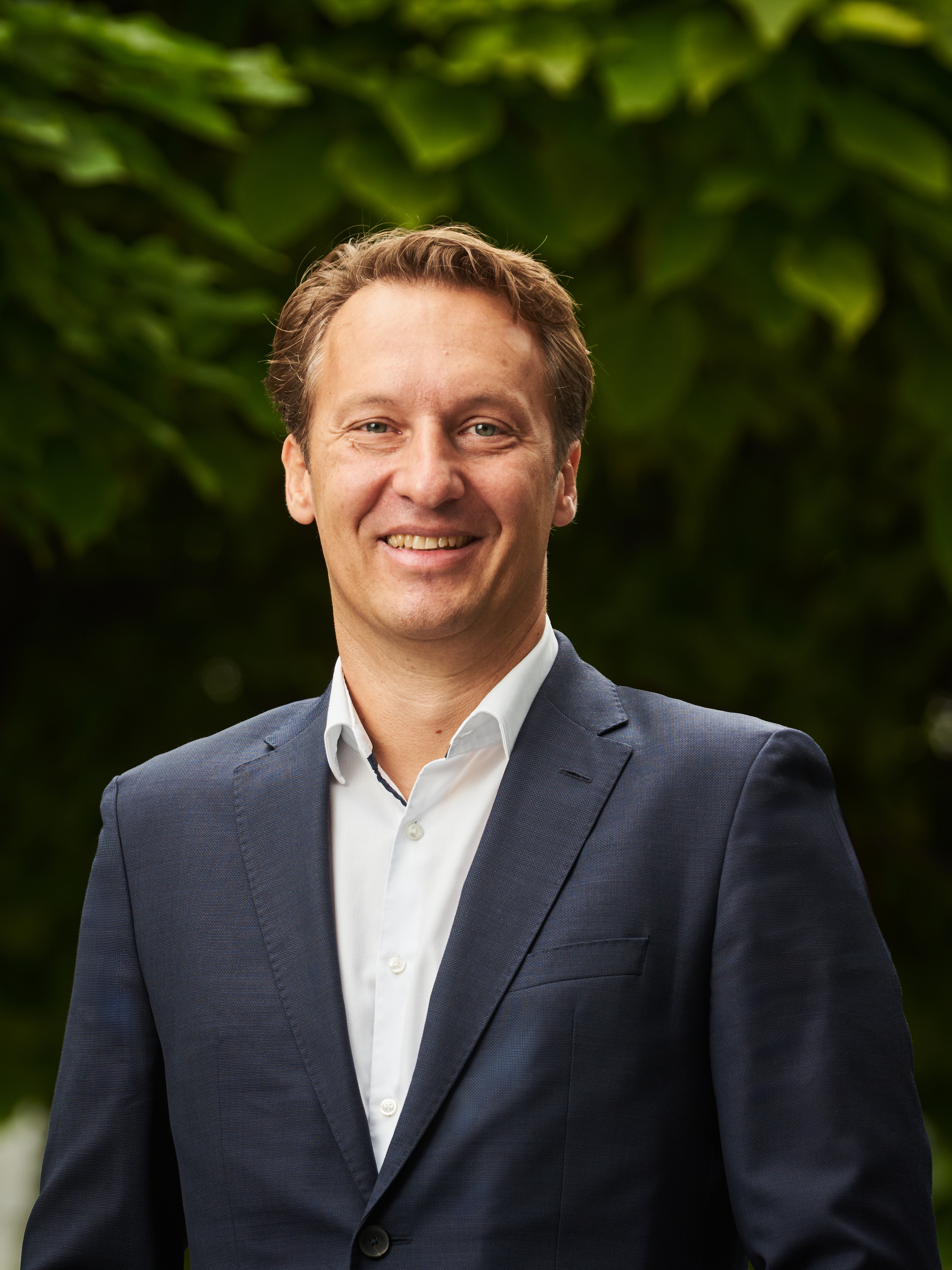 A man in a suit smiles at the camera, matching the CANCOM Austria press release page.