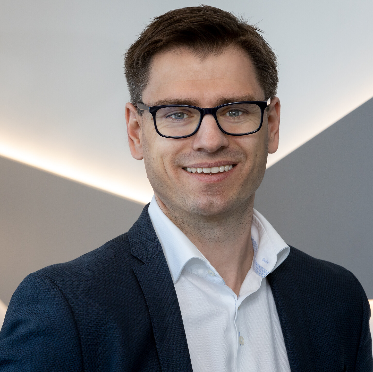 Ein Mann mit Brille und Anzug auf einem Pressefoto von CANCOM Austria.