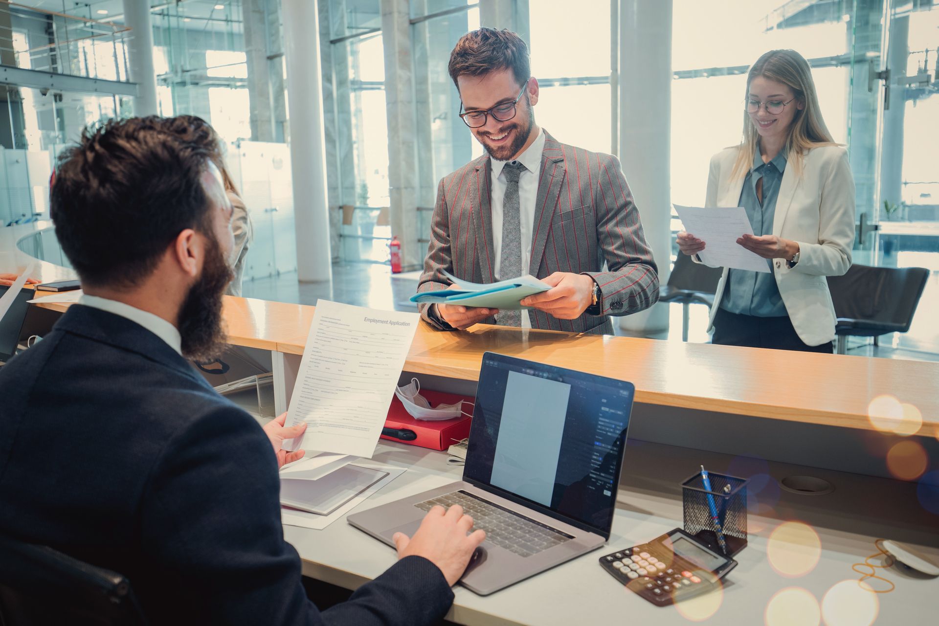 Gruppe von Mitarbeiter:innen arbeitet gemeinsam an einem Schreibtisch mit Laptops in einem Büro.